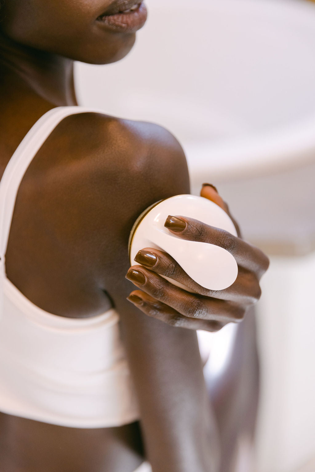 Black Woman using FirmaGlow to exfoliate her shoulder